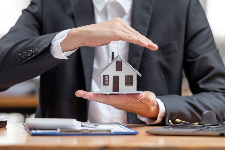 A Man in a Suit Holding a House figure representing Property Insurance and Security Deposits